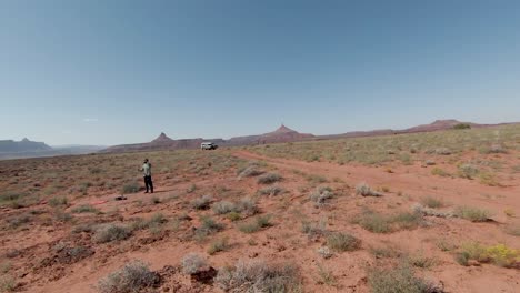 The-guy-has-a-helmet-on-his-head-and-he-controls-a-drone-in-middle-of-desert-and-cliffs-in-Indian-Creek-with-sunny-day