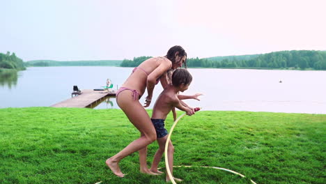 Mom-and-son-playing-on-the-lawn-pouring-water-laughing-and-having-fun-on-the-Playground-with-a-lawn-on-the-background-of-his-house-near-the-lake