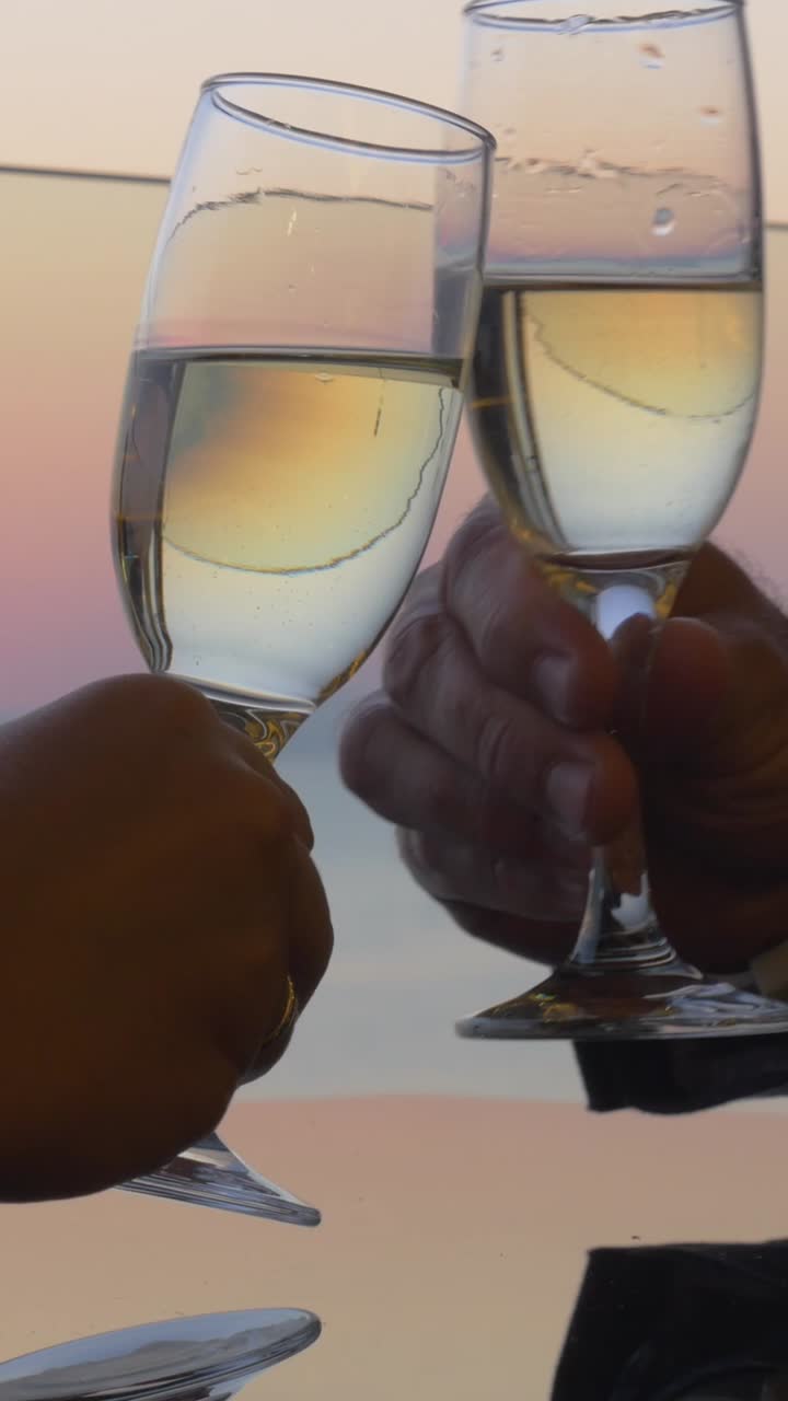 Couple Toasting Wine Glasses at Sunset Over the Ocean