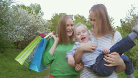 Dos-Mujeres-Con-Un-Niño-Caminando-En-El-Parque-Verde