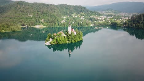 wide aerial view pushing towards an island structure in lake bled, slovenia