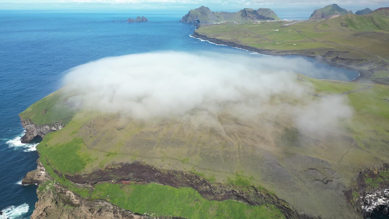 Aerial view of Vestmannaeyjar remote island covered by foggy cloud, spectacular ocean fog in south of Iceland