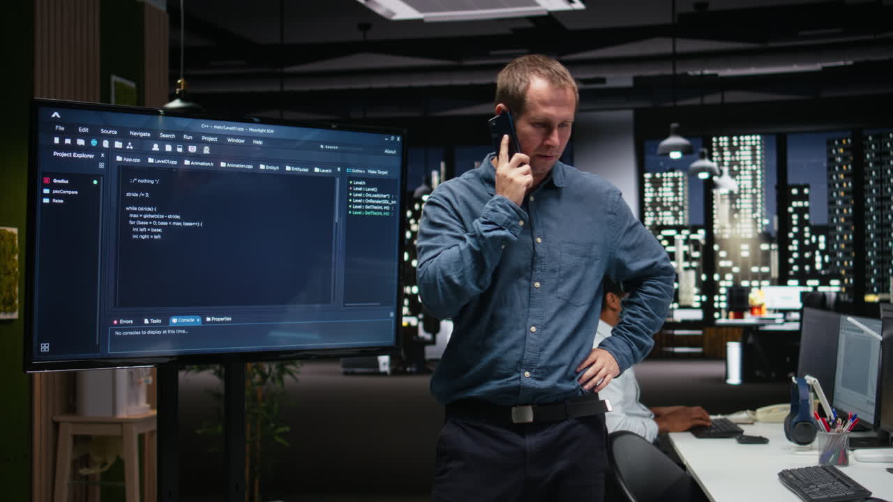 Programmer Talking on Phone and Pointing at Code in Night Office