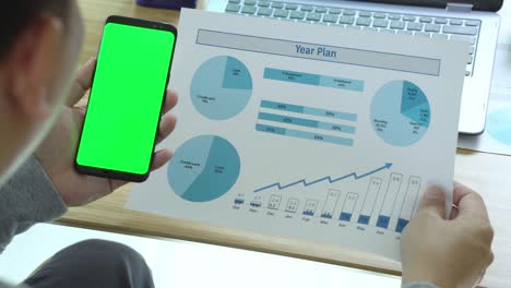 businessman looking on green screen smartphone in office
