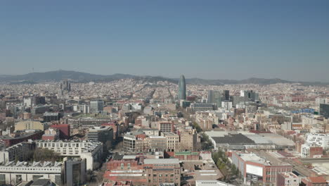 Cityscape-with-Torre-Glories,-tall-modern-skyscraper.-Forwards-fly-above-urban-borough.-Barcelona,-Spain