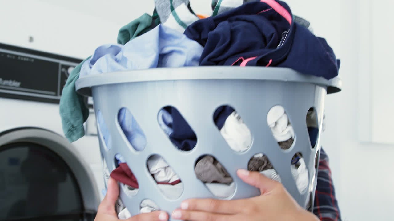 Woman carrying clothes in laundry basket at laundromat 4k