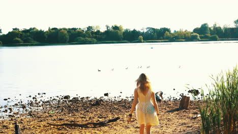 Mujer-Caminando-Hacia-Un-Lago-Con-Patos