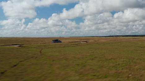 Coche-Familiar-Conduciendo-Por-Una-Carretera-Rodeada-De-Praderas-Planas.-Arroyos-Y-Charcos-En-El-Paisaje.-Campo-En-Un-Día-Soleado.-Dinamarca