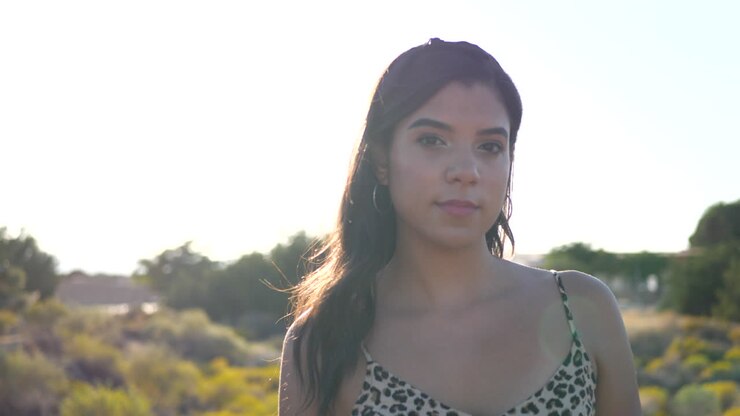 Una hermosa mujer hispana modelando y posando con ojos fijos al aire libre en un paisaje natural desértico.
