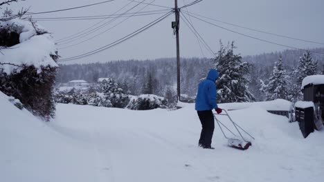 el hombre está quitando nieve del frente de la casa con una gran pala después de una gran tormenta de nieve en noruega