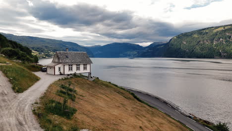 Schönes-Traditionelles-Weißes-Haus-Mit-Steinfüßen-In-Norwegen-Mit-Blick-Auf-Fjord-Und-Berge