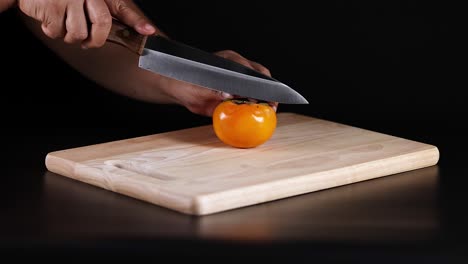 a persimmon being sliced with a knife