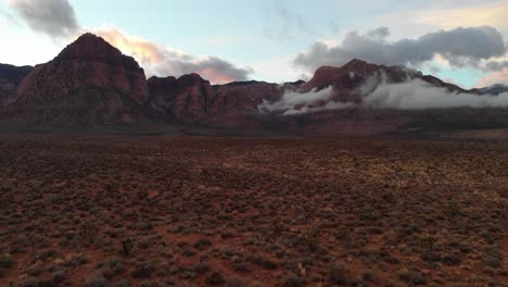 Aerial-drone-shot-with-cloudy-mountains-in-the-background-at-sunset