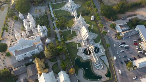 aerial drone birds eye view of wat rong khun the giant buddhist white temple and golden temple with mountains and landscape in chiang rai, thailand