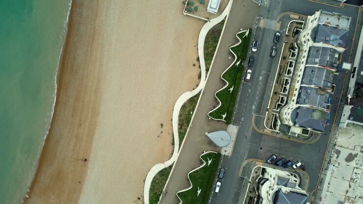 Aerial view of a beach and coastline with cars and buildings