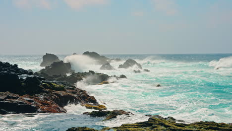 Slow-motion-shot-of-rough-ocean-waves-crushing-against-the-volcanic-rocky-coastline