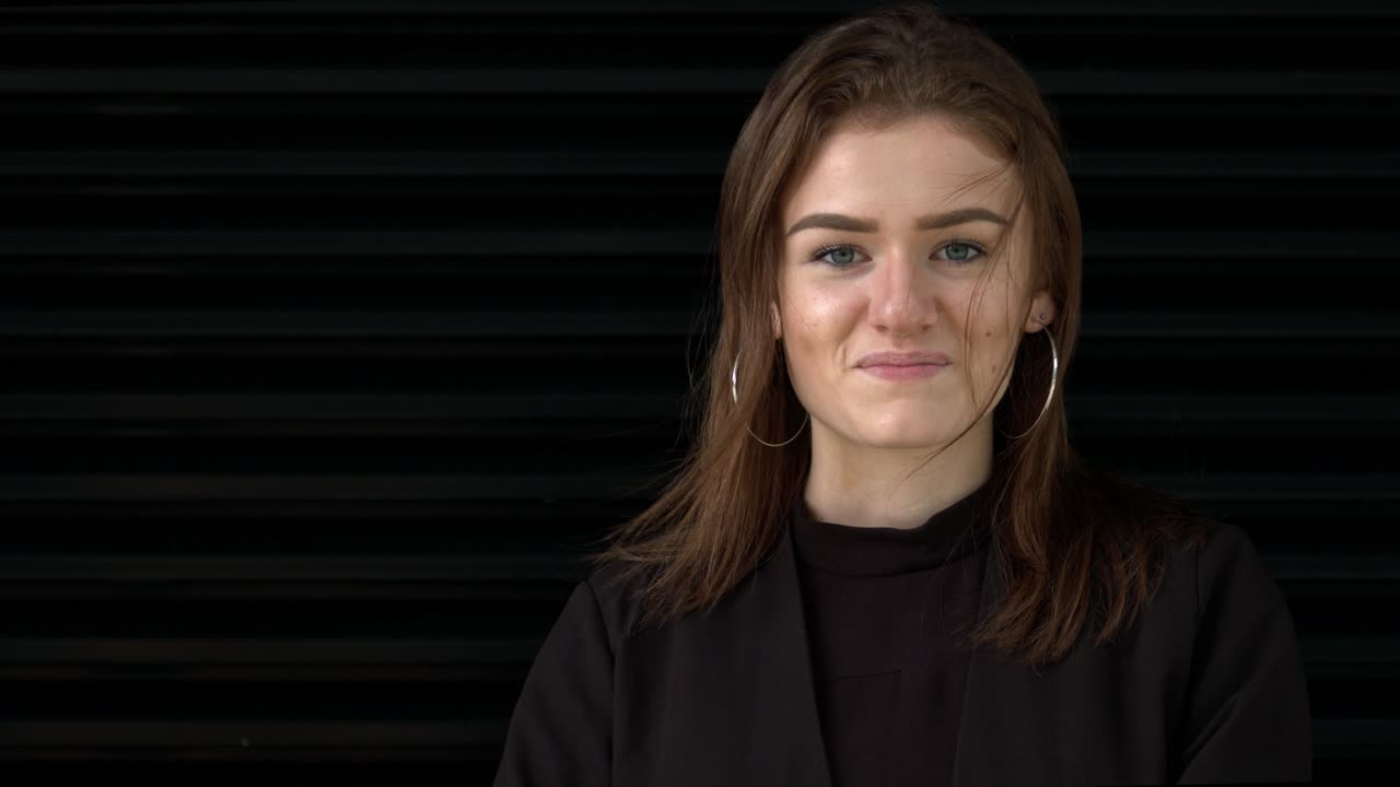 en cámara lenta dramática, una mujer joven con cabello castaño mira hacia la cámara y sonríe