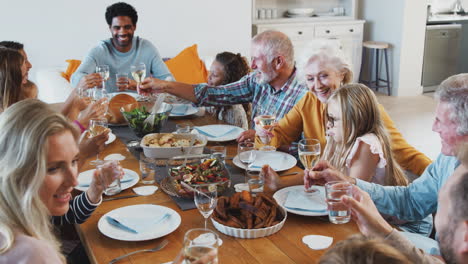 multi-generation family making a toast with wine as they meet for meal at home