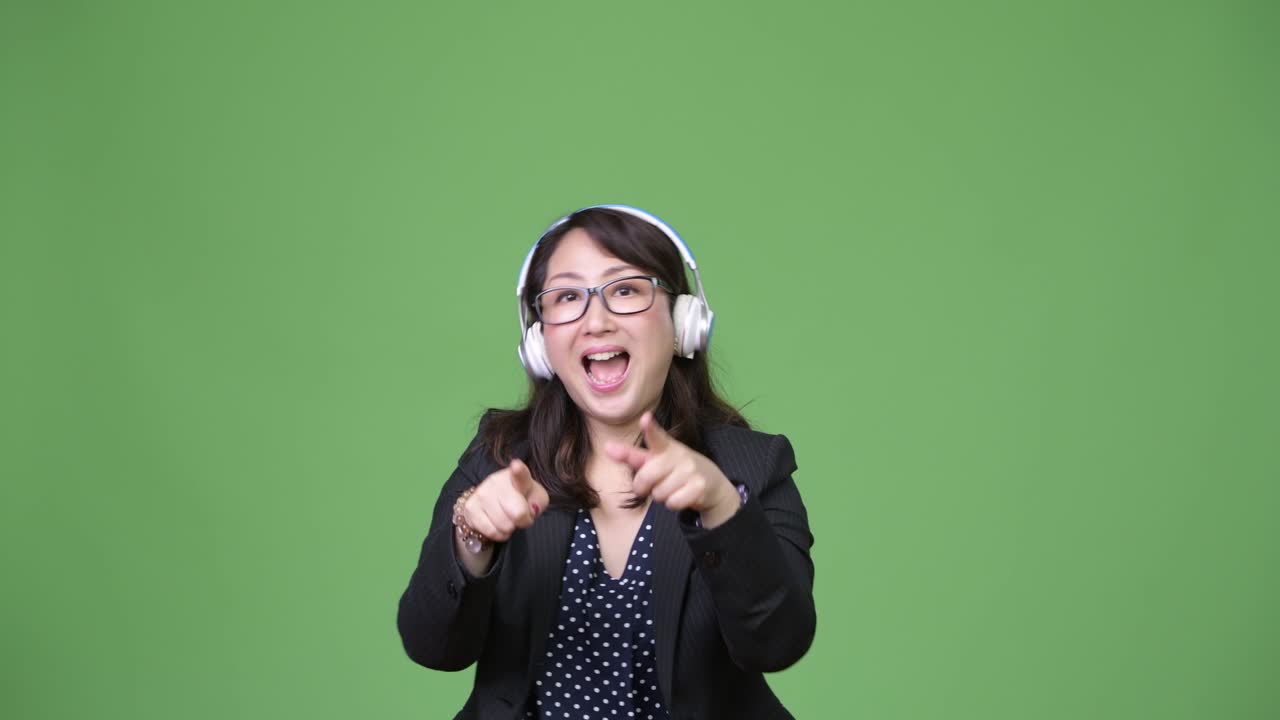 성숙하고 아름다운 아시아 사업가 여성이 음악을 듣고 있습니다.