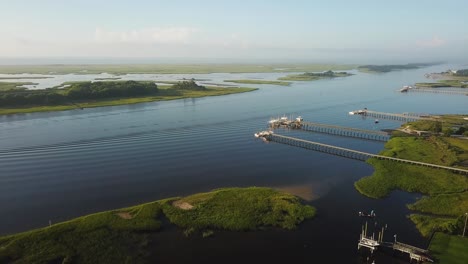 Peaceful-sunrise-drone-right-pan-of-piers,-waterway,-houses,-and-marsh-at-Trails-End-Park-in-Wilmington-North-Carolina