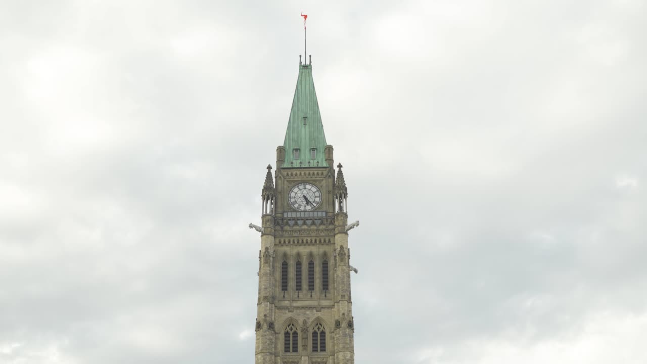 Clock tower spire at Parliament Hill building in Ottawa Ontario Canada with Canadian flag flying in summer