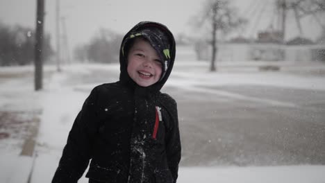 young, happy, smiling boy wearing a coat playing outside throws snow in the air while laughing on a cold, winter day in december during christmas break in a small town in the midwest