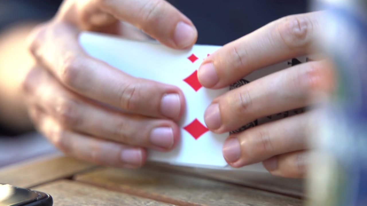 Primer plano de las manos de un hombre intentando barajar una baraja de cartas. Manos de un joven mezclando cartas. Primer plano y enfoque selectivo.