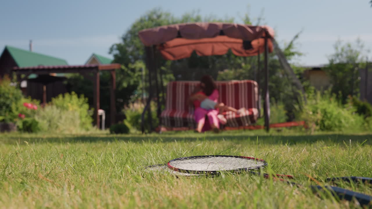 Young Girl Resting On Outdoor Swing Seat, Caucasian Girl Relaxing On Swing In Sunny Outdoor Setting, Young Girl From Caucasian Background Paused On Swing Amidst Sunny Garden Scene During Playtime