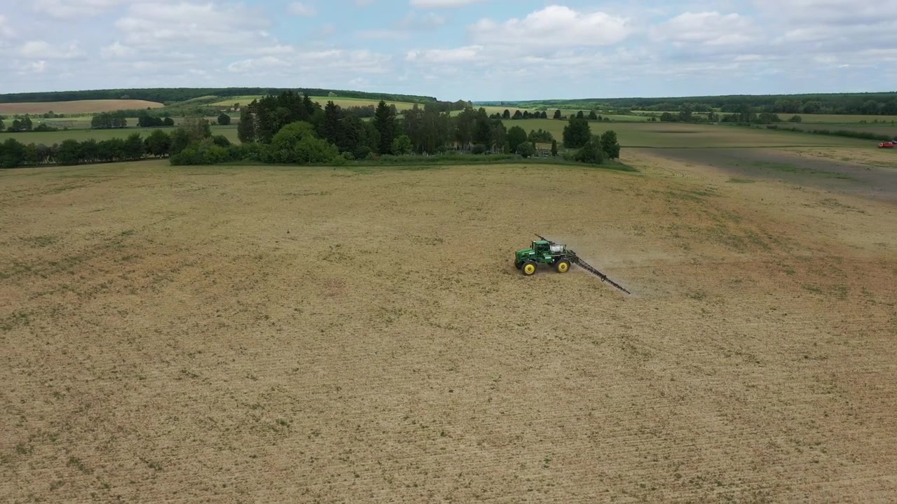Trattore agricolo che irrora fertilizzante su un vasto campo