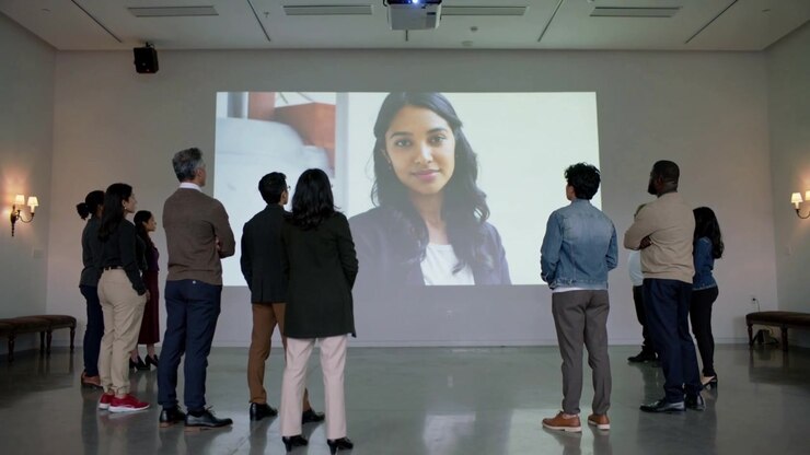 Projector starting, staff wearing casual clothes watching portrait on screen in gallery for talk