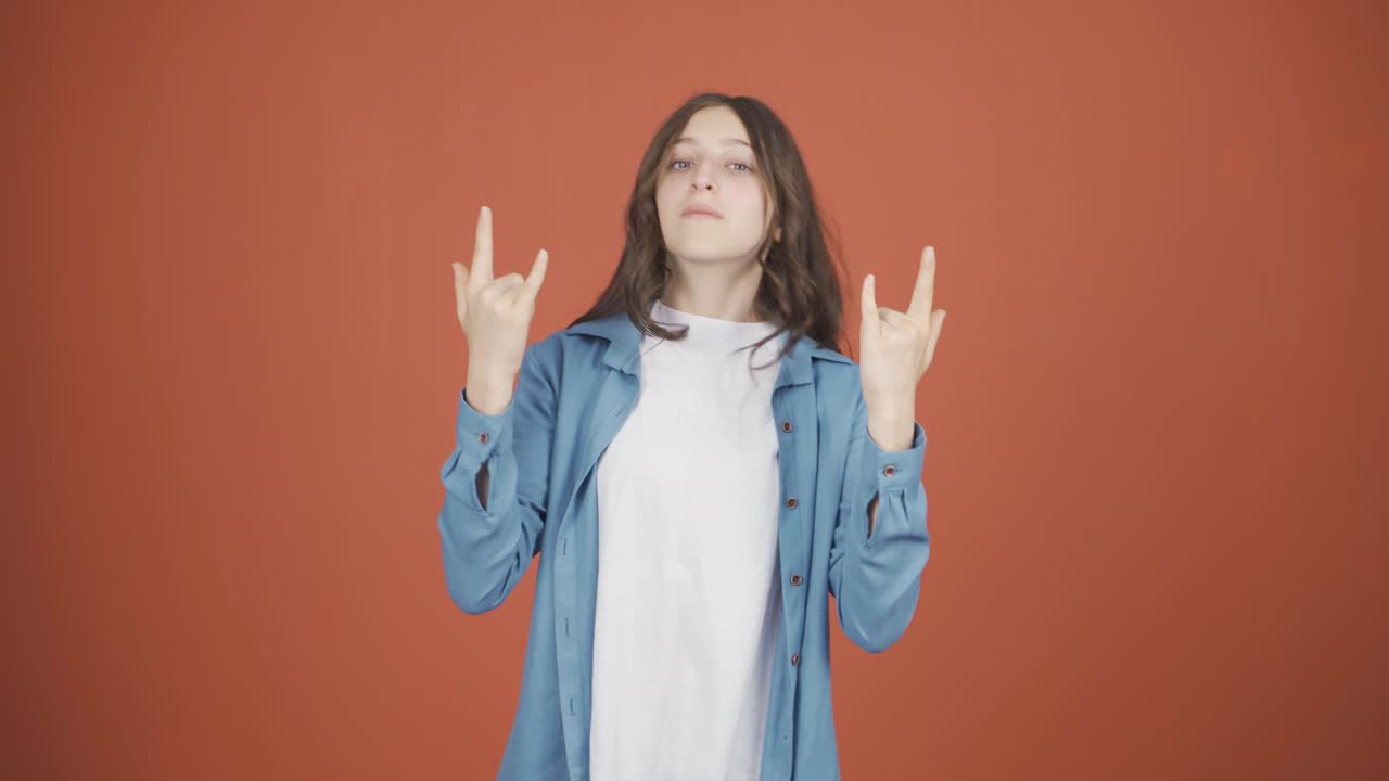 젊은 여성이 로커 기호를 하고 춤을 추고 있습니다.