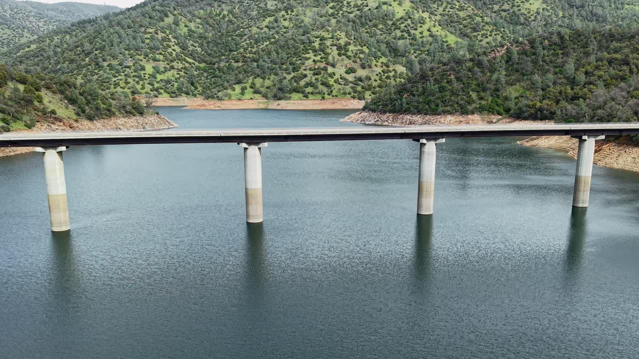 The Don Pedro Reservoir Bridge stands tall in this aerial footage, linking roads over the shimmering California waters.