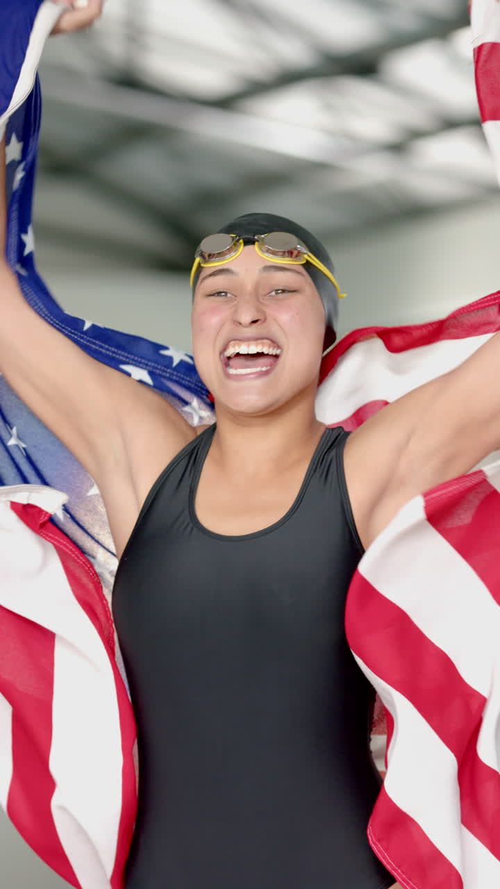 Vertical video: Celebrating victory, swimmer holding American flag and smiling in swim cap