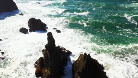 gorgeous aerial shot of formed sea stacks with turbulent ocean waves crashing on the rocks off the shore of oregon, pacific northwest