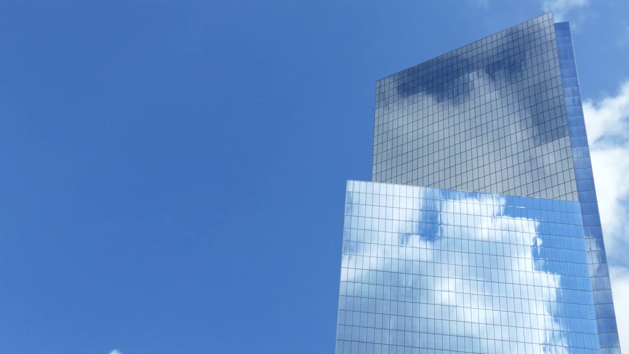 Modern Skyscraper Against a Blue Sky with Cloud Reflections