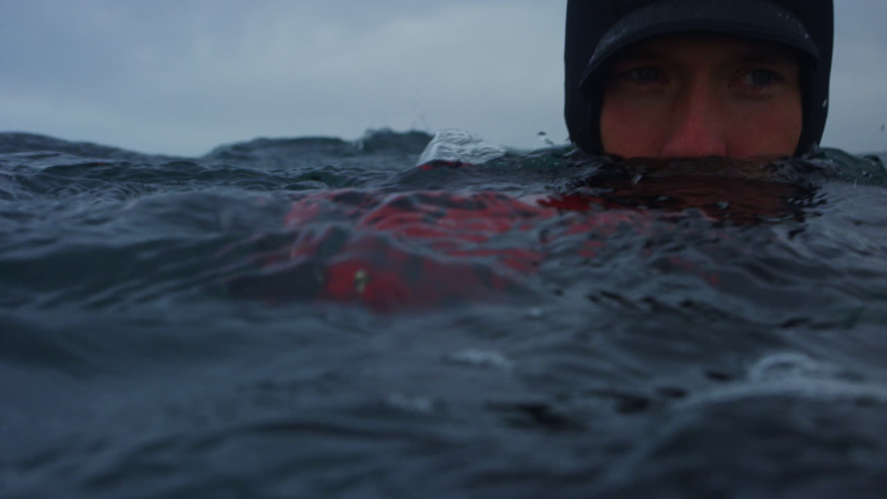 Profile of surf photographer floating in lineup watching sets approach from horizon