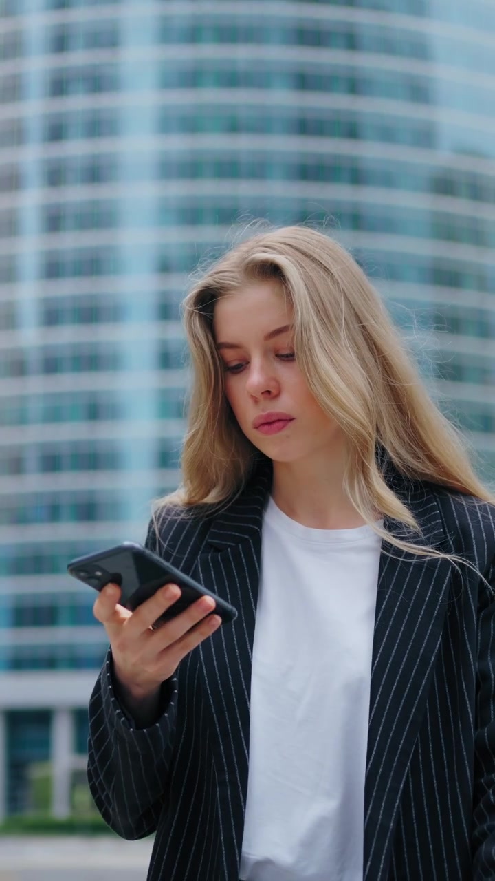 Giovane professionista che usa lo smartphone fuori da un moderno edificio per uffici