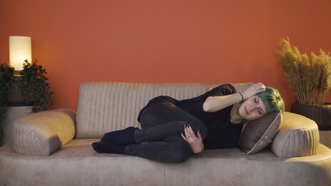 una giovane donna depressa sdraiata sul divano.