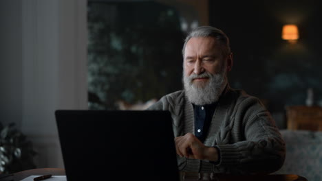 senior man having video call online at laptop computer