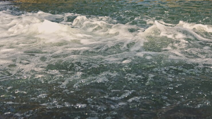 Flusso d'acqua da una sorgente. Forte corrente di acqua di fiume. Flusso d'acqua sui sassi in un fiume