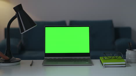 zooming shot of working place in apartment notebook with green screen lamp and books for remote work and using laptop interior of modern apartment