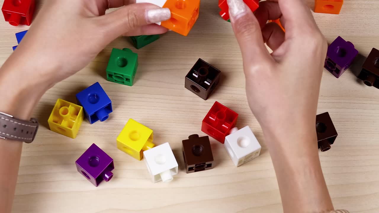Hands arranging vibrant cubes on a wooden surface, showcasing organization and creativity.