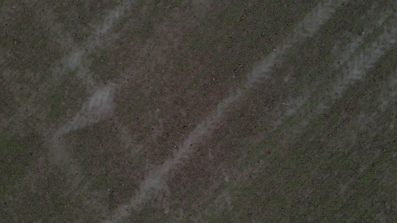 un disparo de avión no tripulado despegando y ascendiendo sobre un campo de granja húmedo y fangoso