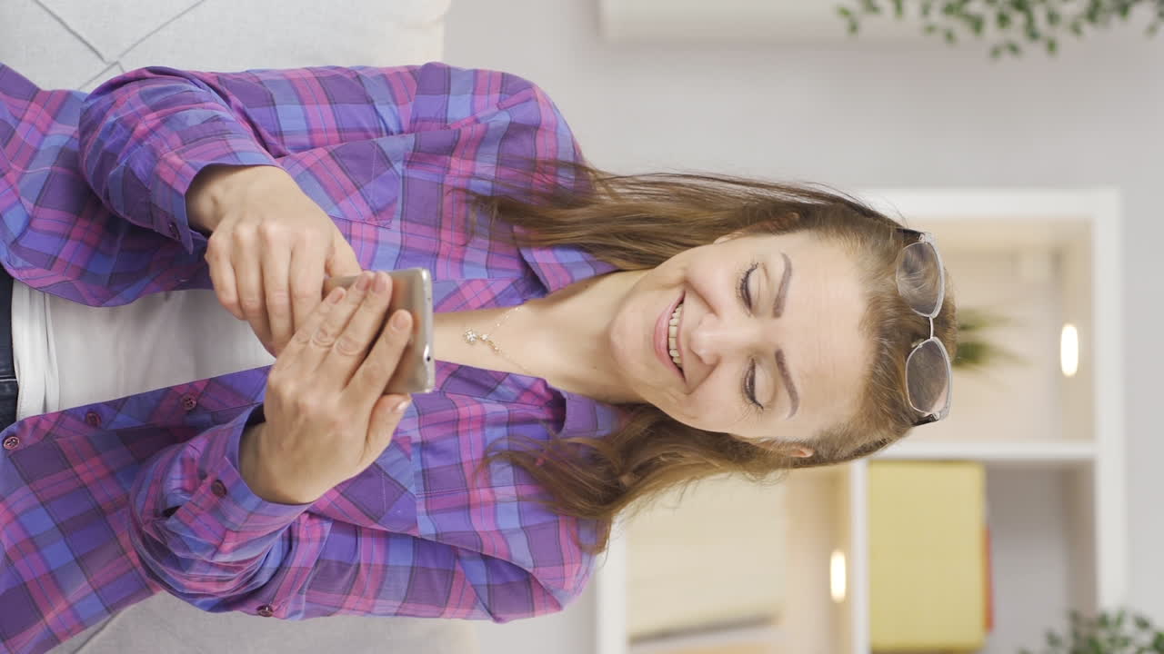 video vertical de una mujer riendo de un mensaje telefónico.
