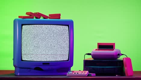 old television with grey interference screen on purple neon background. close-up of vintage tv and cartridges for retro playstation. antique video game, nostalgia