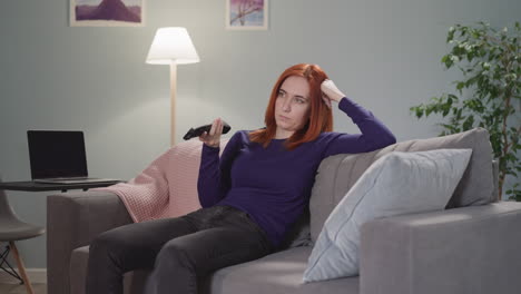 powerless woman with ginger hair watches tv after work