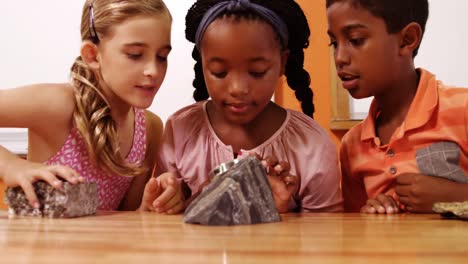 niños de la escuela usando lupa sobre la roca