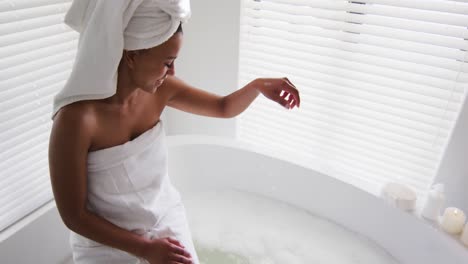 african american woman touching water in the bath tub in the bathroom at home