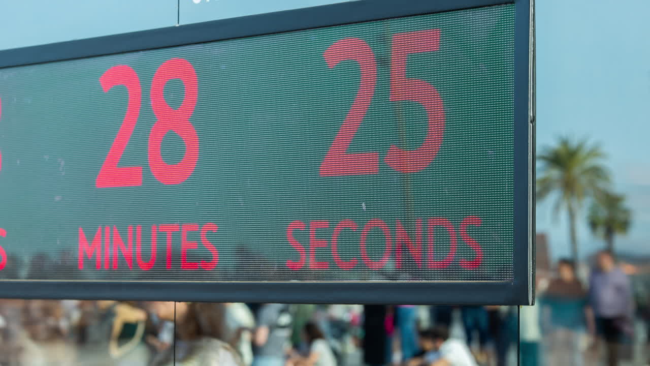 Люди на барселонском пляже отражаются в зеркальной стене с таймером обратного отсчета