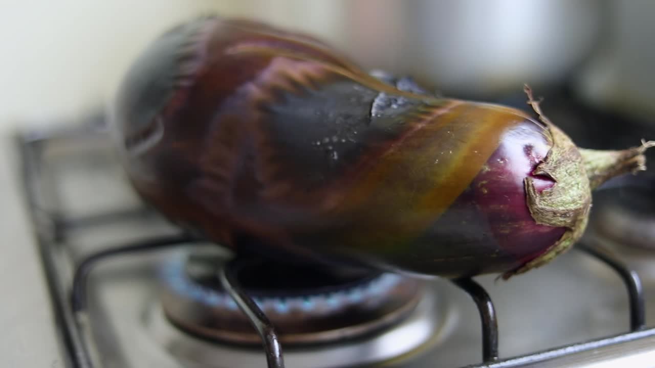 Färsk stor aubergine rostad över spisen i köket